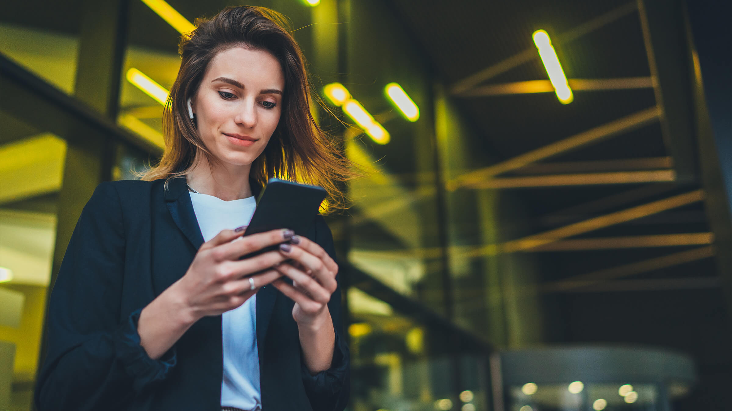 Person using smartphone outdoors with yellow background}